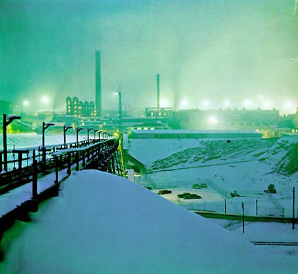 A photo of the Bunker Hill Smelter operating at night in the snow