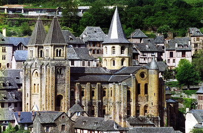Saint Foy abbey-church in Conques, France, a stone building with medieval-style turrets surrounded by aesthetically similar village architecture