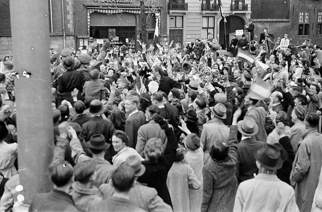A large crowd stands in front of a building