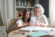 A woman looks at a phone with her granddaughter