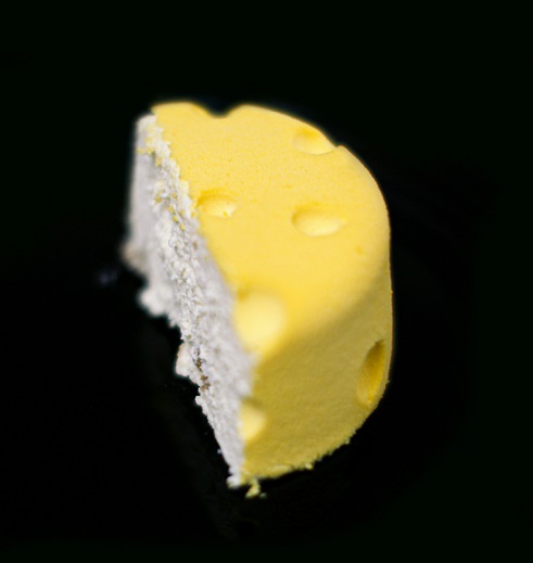 A piece of soft cheese cut in half on a black background, reminiscent of the Moon