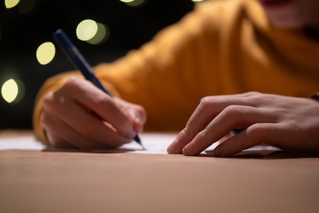 Photo of person's hands holding pen over a sheet of paper on a table