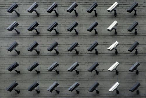 Security cameras laid out in a grid pattern on a gray brick wall