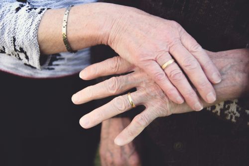 Photo of two hands touching, both with wedding bands