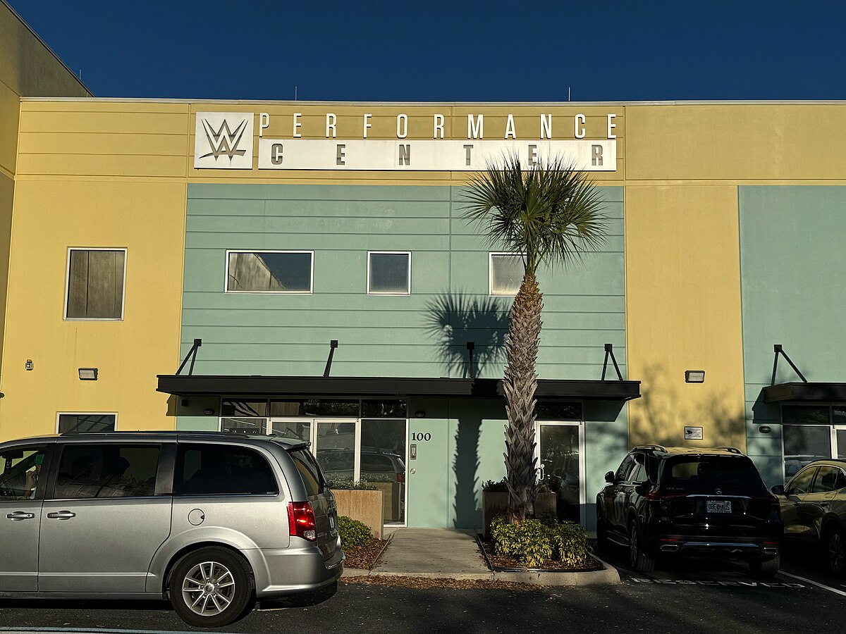 Yellow and grey facade of the WWE Performance Center in Orlando with a palm tree out front